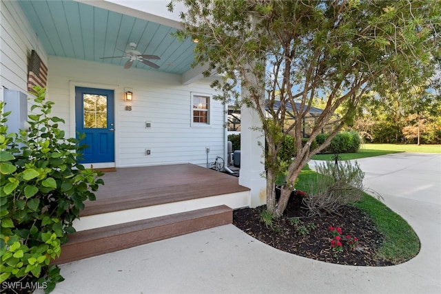 view of exterior entry featuring ceiling fan and a deck