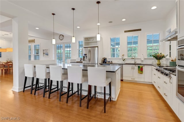 kitchen with white cabinets, appliances with stainless steel finishes, and light hardwood / wood-style flooring