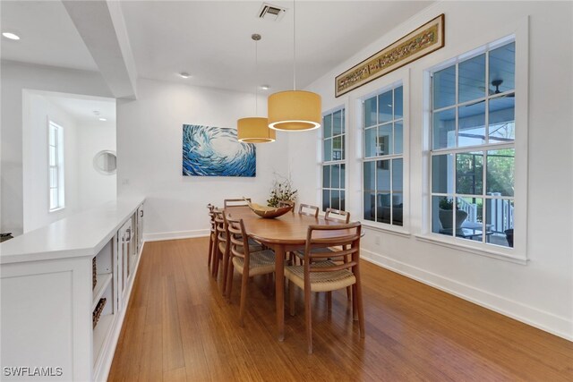 dining space with a wealth of natural light, beamed ceiling, and hardwood / wood-style flooring