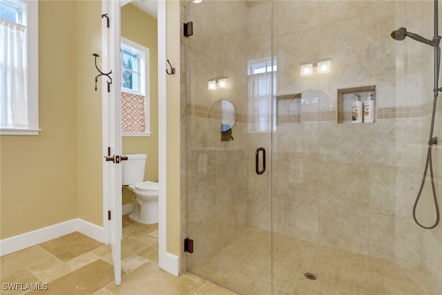 bathroom featuring an enclosed shower, plenty of natural light, and toilet