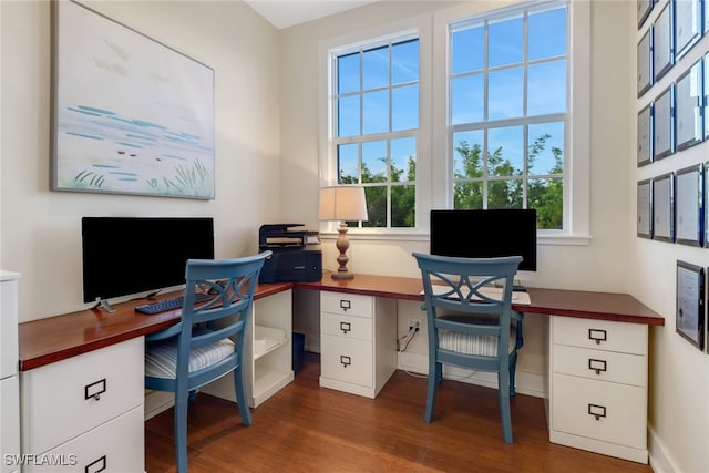 office with dark hardwood / wood-style flooring, plenty of natural light, and built in desk