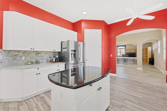 kitchen with ceiling fan, dark stone countertops, backsplash, white cabinets, and stainless steel fridge with ice dispenser