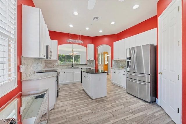 kitchen featuring white cabinetry, tasteful backsplash, a center island, hanging light fixtures, and appliances with stainless steel finishes