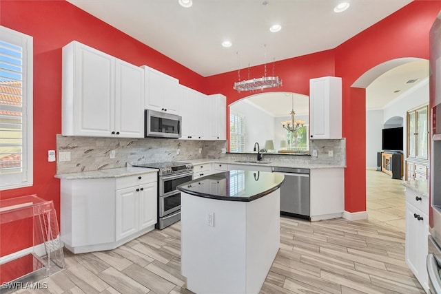 kitchen featuring stainless steel appliances, a center island, sink, and white cabinets