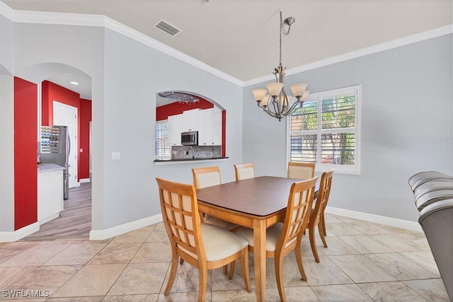 tiled dining space featuring ornamental molding and an inviting chandelier