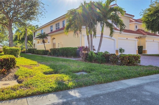 mediterranean / spanish-style home with a garage and a front lawn