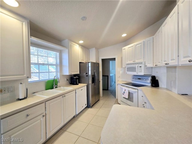 kitchen with sink, white cabinetry, a textured ceiling, light tile patterned floors, and white appliances