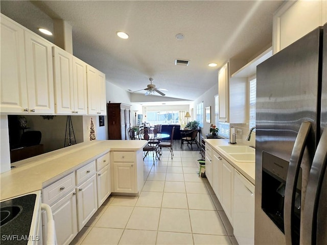 kitchen with lofted ceiling, sink, stainless steel fridge, white cabinetry, and kitchen peninsula