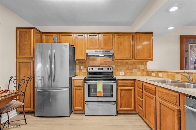 kitchen featuring stainless steel appliances, tasteful backsplash, sink, and light wood-type flooring