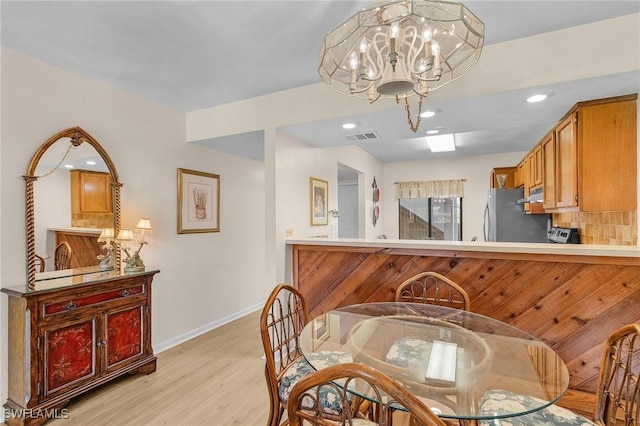 dining area with light hardwood / wood-style floors and a notable chandelier