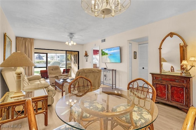 dining room with ceiling fan with notable chandelier and light hardwood / wood-style flooring