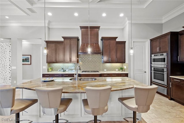 kitchen featuring sink, custom range hood, a kitchen island with sink, and hanging light fixtures