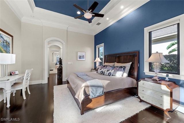 bedroom with a raised ceiling, ornamental molding, dark wood-type flooring, and ceiling fan