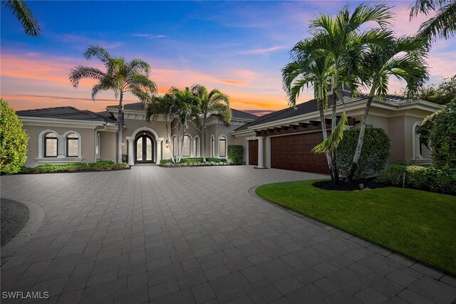 mediterranean / spanish house featuring french doors, a garage, and a lawn