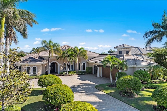 mediterranean / spanish-style home featuring a garage and a front yard