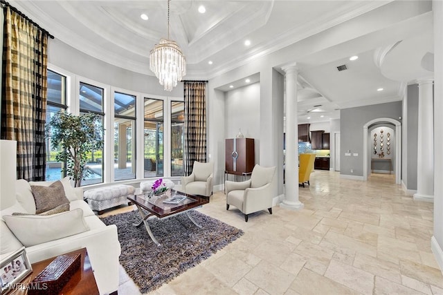 living room featuring crown molding, a tray ceiling, a chandelier, and decorative columns