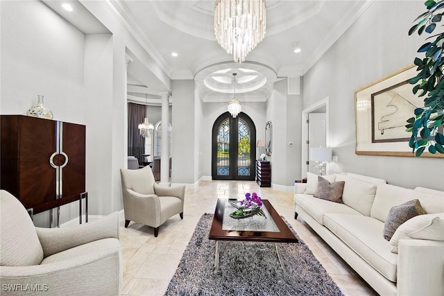 living room featuring a towering ceiling, decorative columns, a notable chandelier, crown molding, and french doors