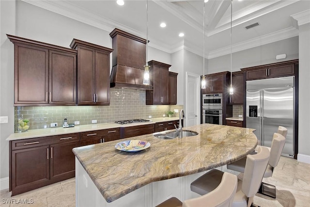 kitchen featuring a kitchen island with sink, sink, stainless steel appliances, and custom range hood