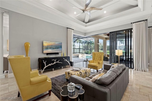 living room featuring ceiling fan, ornamental molding, a tray ceiling, and ornate columns