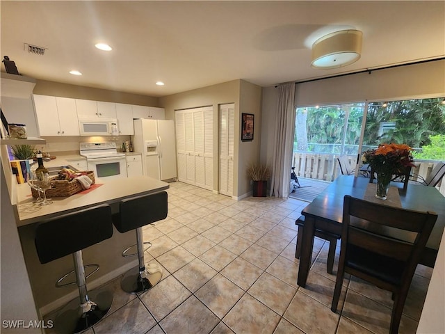 kitchen featuring white appliances, white cabinetry, and light tile patterned floors