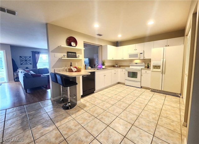 kitchen with sink, white cabinetry, light tile patterned floors, white appliances, and a breakfast bar