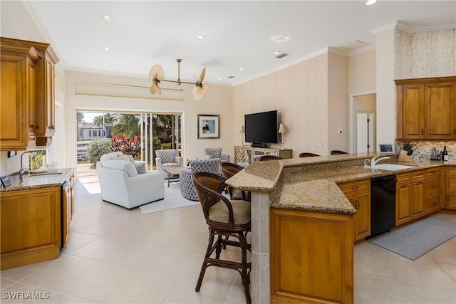 kitchen with sink, black dishwasher, light stone counters, kitchen peninsula, and a breakfast bar area