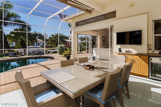 view of patio featuring a lanai, wine cooler, a bar, and an outdoor kitchen