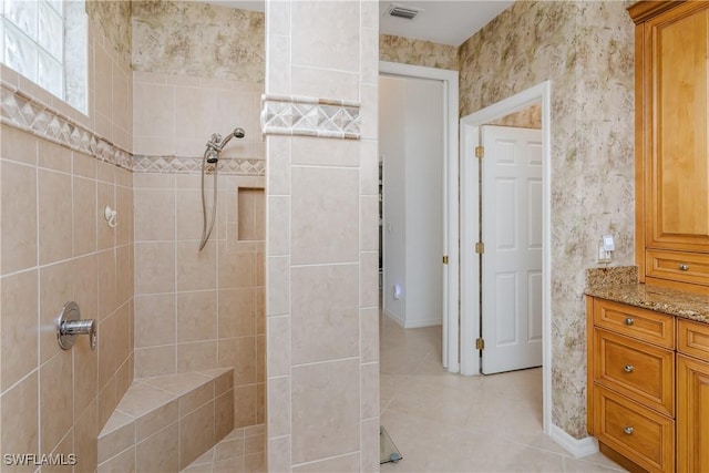 bathroom featuring tile patterned flooring, vanity, and tiled shower