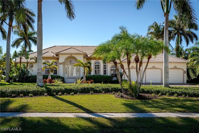 mediterranean / spanish-style home with a front lawn and a garage