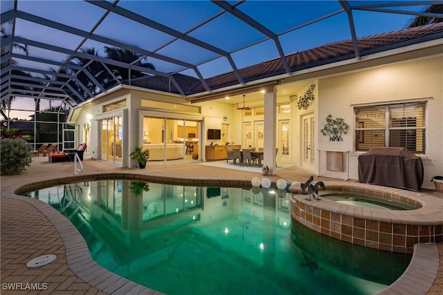 pool at dusk featuring glass enclosure, french doors, area for grilling, an in ground hot tub, and a patio