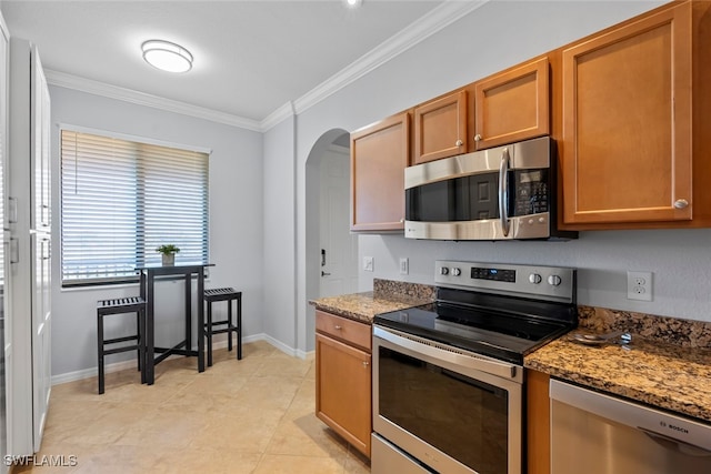 kitchen with stainless steel appliances, crown molding, dark stone counters, and light tile patterned flooring