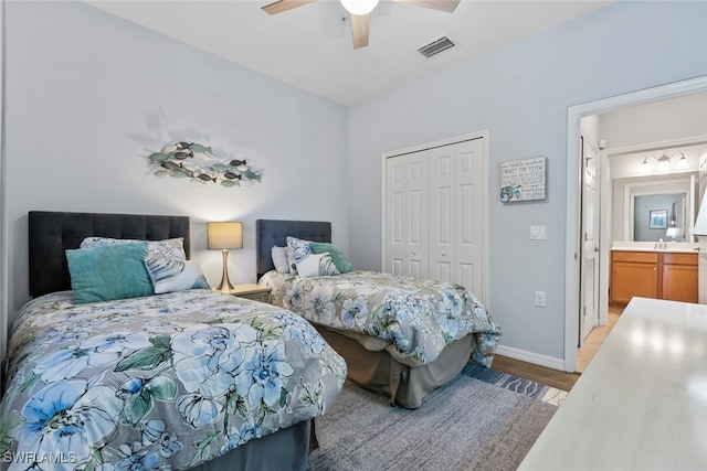 bedroom featuring a closet, light hardwood / wood-style flooring, ceiling fan, and ensuite bathroom