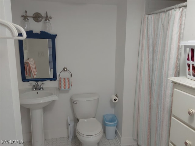 bathroom with tile patterned flooring, curtained shower, toilet, and sink