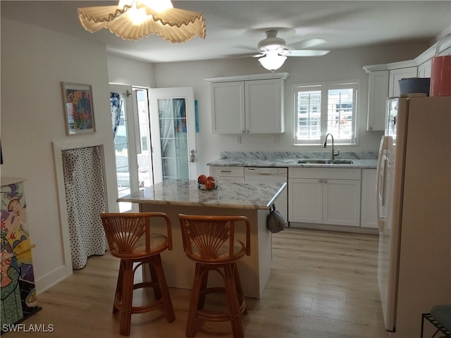 kitchen featuring white refrigerator with ice dispenser, white cabinets, sink, light hardwood / wood-style flooring, and a kitchen island