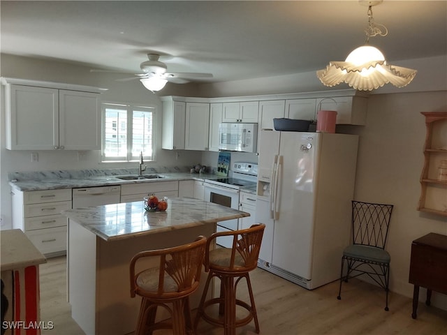 kitchen with white appliances, sink, pendant lighting, white cabinets, and a kitchen island