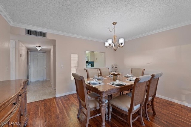 dining area with an inviting chandelier, crown molding, dark wood-type flooring, and a textured ceiling