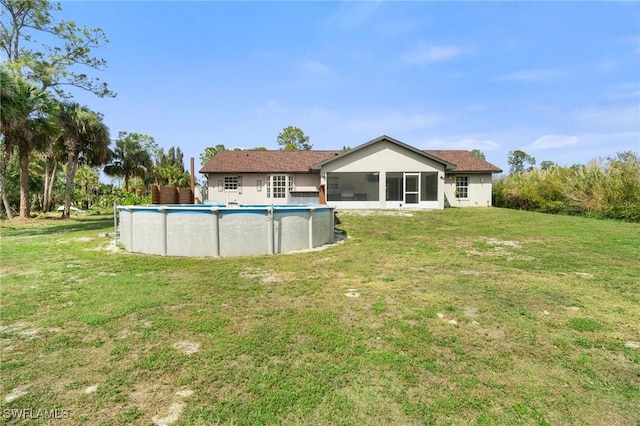 rear view of house featuring a sunroom, an outdoor pool, and a lawn