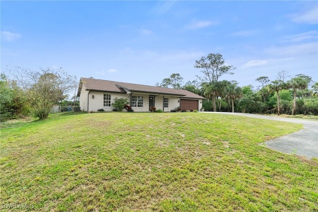 single story home with a garage, driveway, a front lawn, and stucco siding