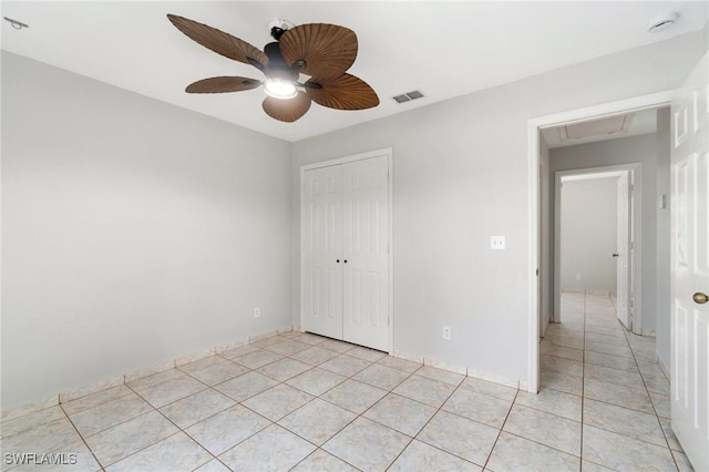 unfurnished bedroom featuring attic access, visible vents, ceiling fan, a closet, and light tile patterned flooring