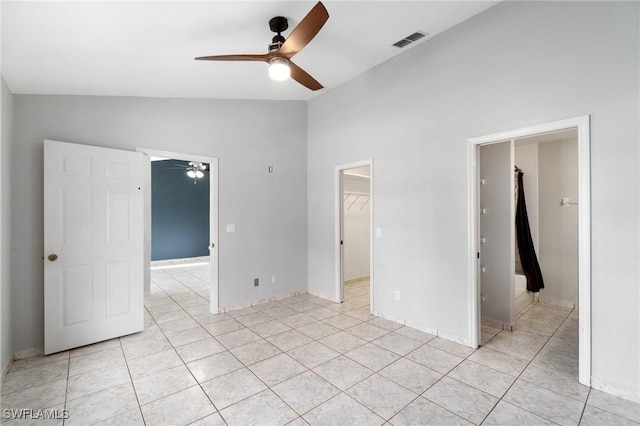 unfurnished bedroom with a walk in closet, light tile patterned floors, lofted ceiling, a closet, and visible vents