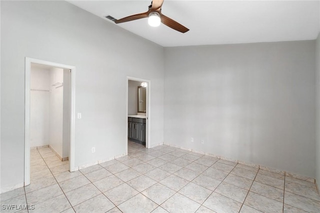 unfurnished bedroom with visible vents, lofted ceiling, ceiling fan, a walk in closet, and light tile patterned flooring