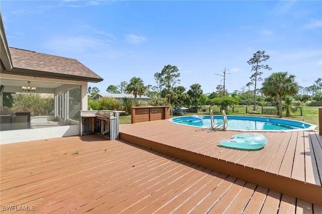 outdoor pool with a sunroom and a deck