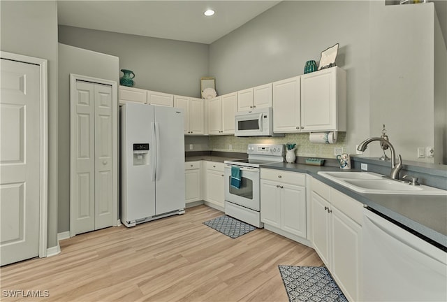 kitchen with white cabinetry, sink, white appliances, and light hardwood / wood-style flooring