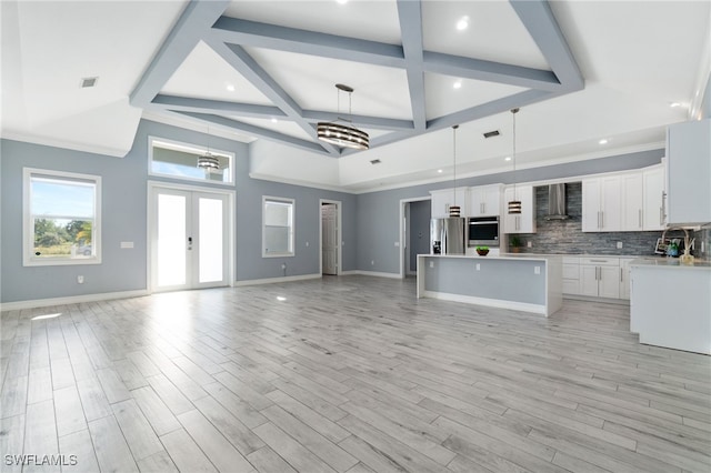 kitchen featuring pendant lighting, a kitchen island, white cabinets, wall chimney range hood, and backsplash