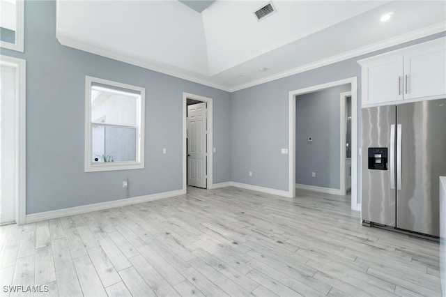 interior space with stainless steel fridge with ice dispenser, light wood-type flooring, crown molding, a tray ceiling, and white cabinets