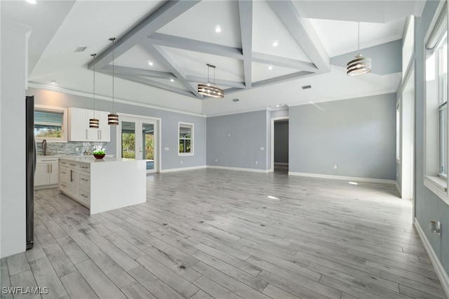 unfurnished living room featuring coffered ceiling, light wood-type flooring, crown molding, and beamed ceiling