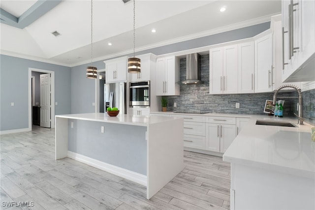 kitchen with decorative light fixtures, wall chimney range hood, a center island, and appliances with stainless steel finishes