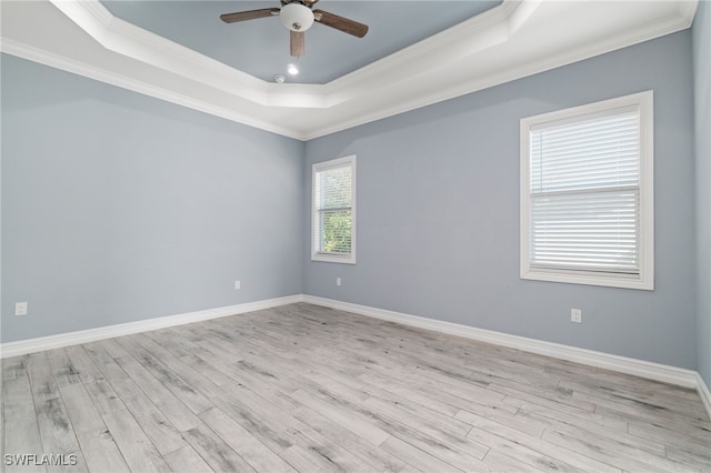 unfurnished room featuring light wood-type flooring, ornamental molding, a raised ceiling, and ceiling fan