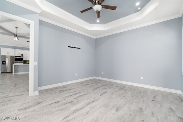 empty room featuring ceiling fan, crown molding, light hardwood / wood-style flooring, and a raised ceiling