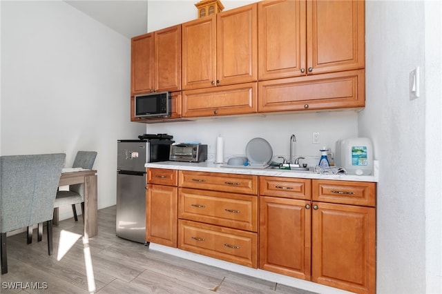 kitchen featuring light wood-type flooring and stainless steel fridge